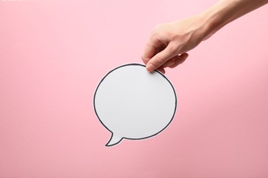 Photo of Woman holding blank speech bubble on light pink background, closeup. Space for text