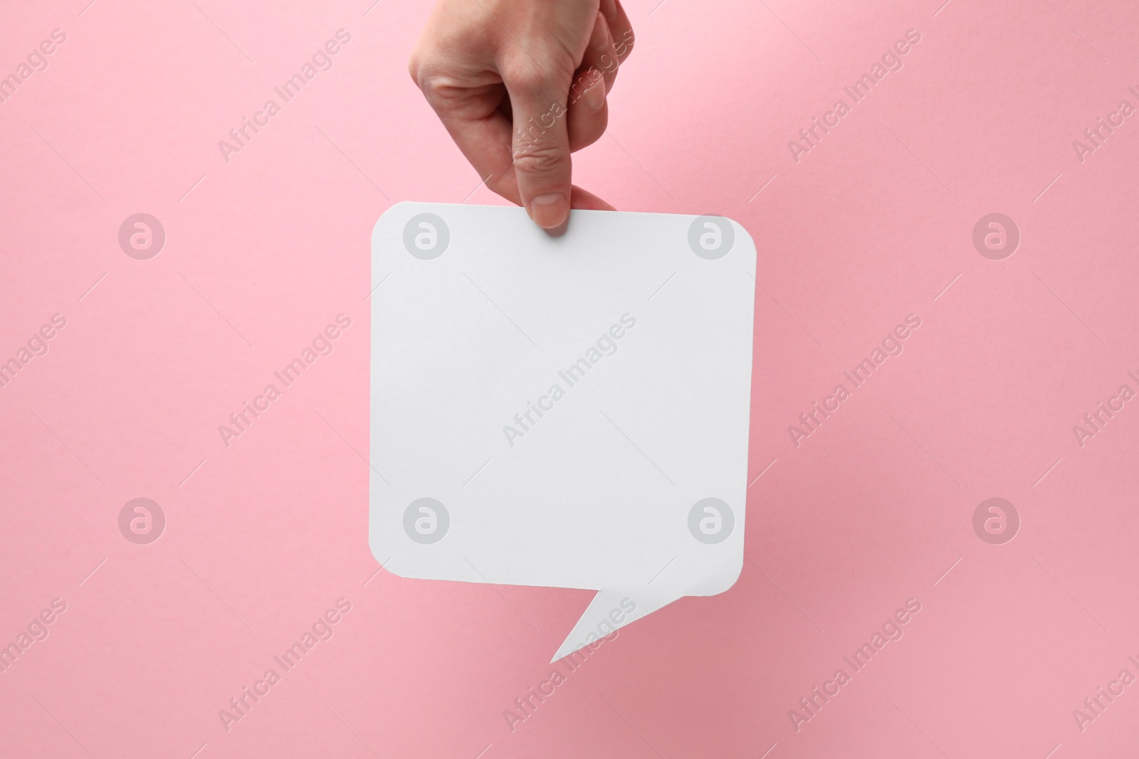 Photo of Woman holding blank speech bubble on light pink background, closeup. Space for text