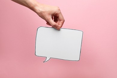 Photo of Woman holding blank speech bubble on light pink background, closeup. Space for text