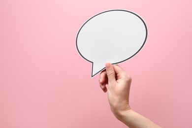 Photo of Woman holding blank speech bubble on light pink background, closeup. Space for text