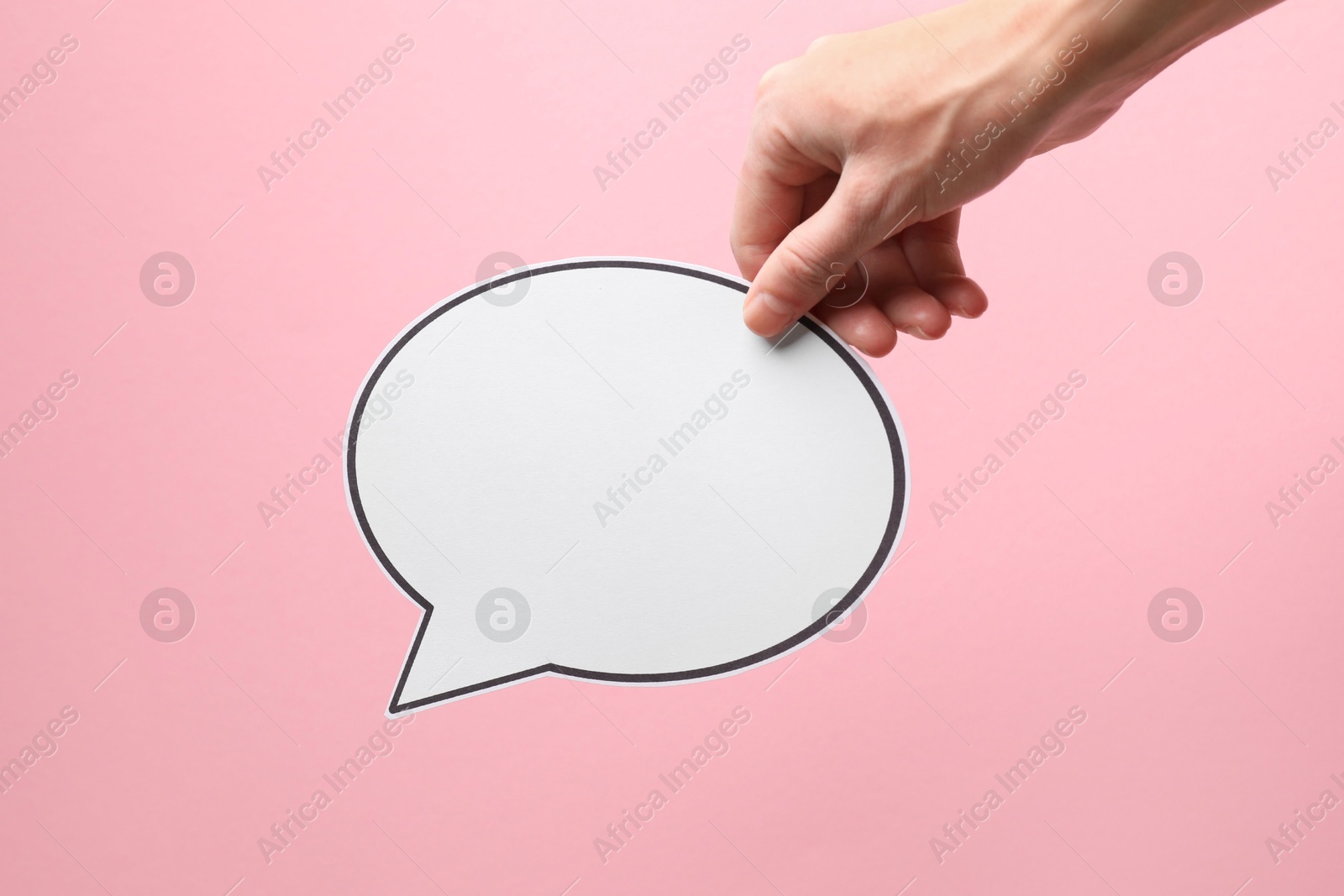 Photo of Woman holding blank speech bubble on light pink background, closeup. Space for text