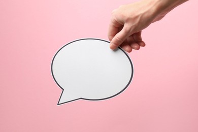 Photo of Woman holding blank speech bubble on light pink background, closeup. Space for text