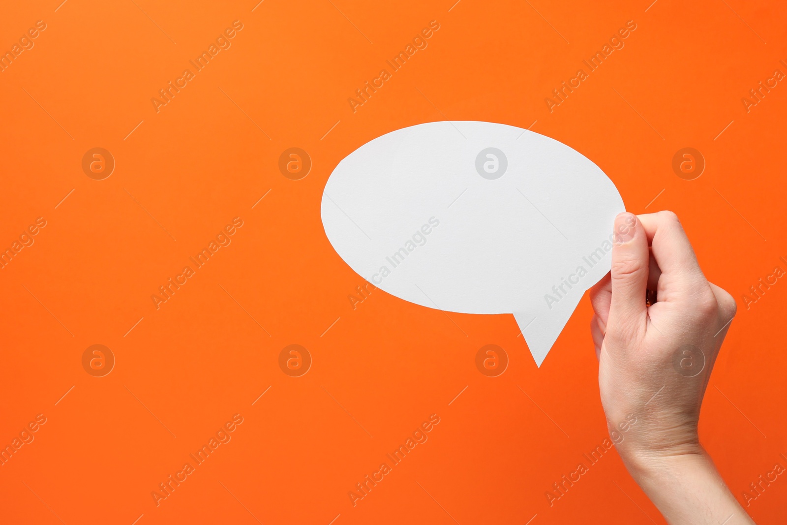 Photo of Woman holding blank speech bubble on orange background, closeup. Space for text