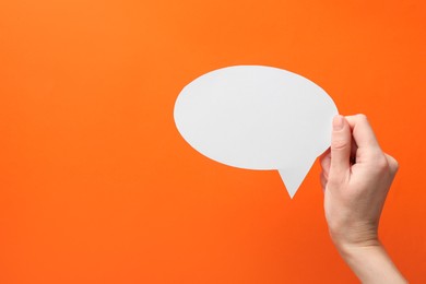 Photo of Woman holding blank speech bubble on orange background, closeup. Space for text