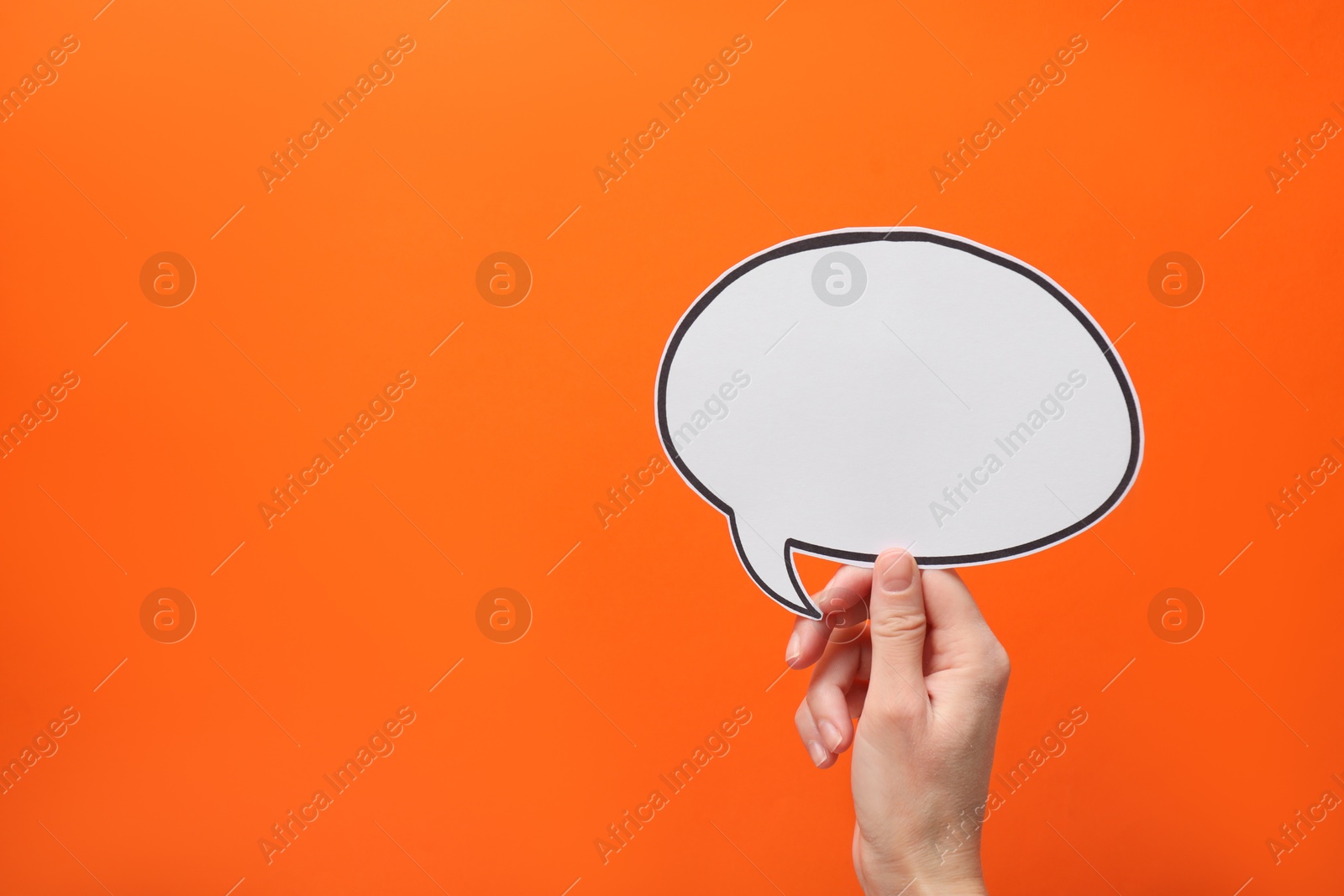 Photo of Woman holding blank speech bubble on orange background, closeup. Space for text