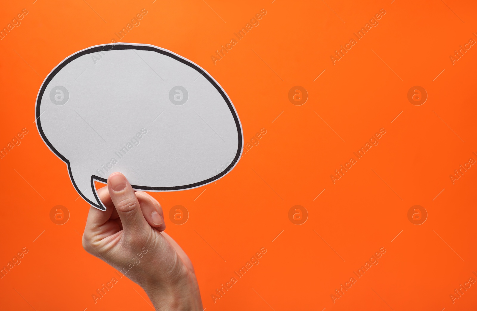 Photo of Woman holding blank speech bubble on orange background, closeup. Space for text