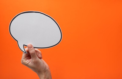 Photo of Woman holding blank speech bubble on orange background, closeup. Space for text