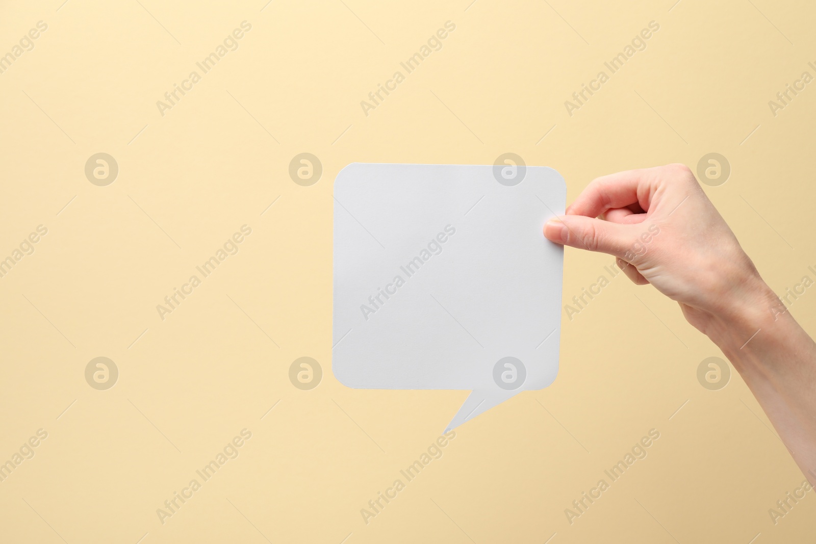 Photo of Woman holding blank speech bubble on beige background, closeup. Space for text