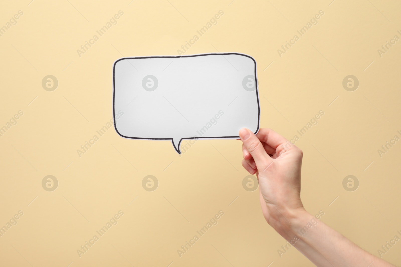 Photo of Woman holding blank speech bubble on beige background, closeup. Space for text