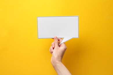 Photo of Woman holding blank speech bubble on yellow background, closeup. Space for text