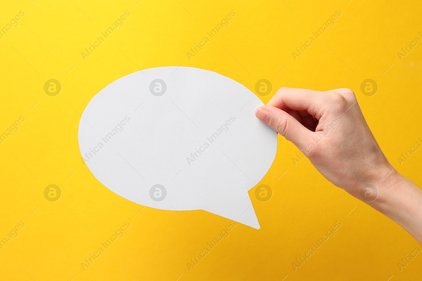 Photo of Woman holding blank speech bubble on yellow background, closeup. Space for text