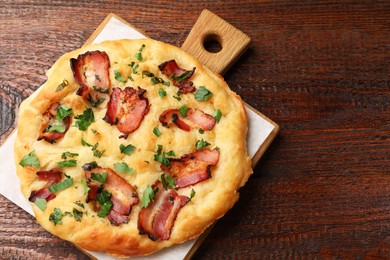 Photo of Delicious focaccia bread with bacon and parsley on wooden table, top view