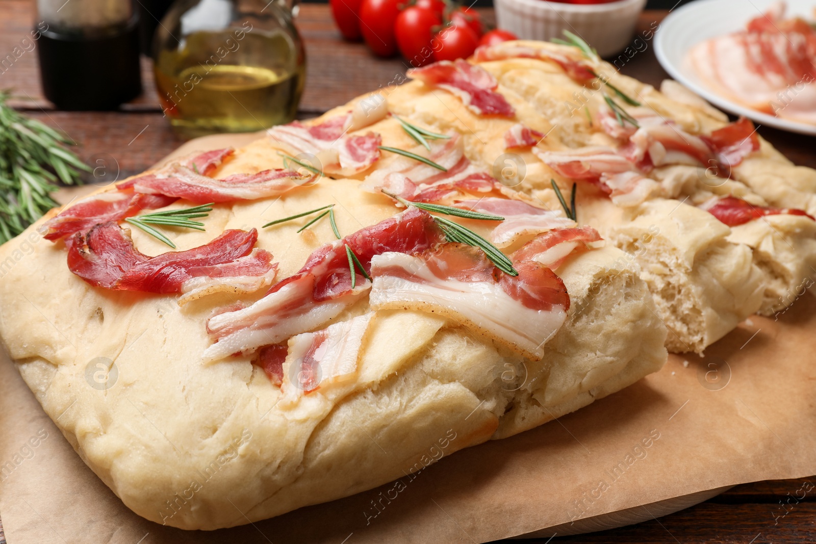 Photo of Slices of delicious focaccia bread with bacon and rosemary on table, closeup