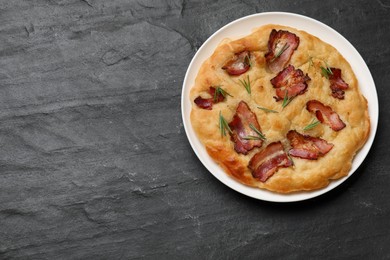 Photo of Delicious focaccia bread with bacon and rosemary on black table, top view. Space for text