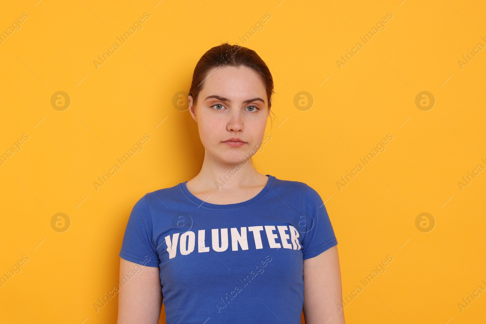 Photo of Portrait of woman in t-shirt with word Volunteer on orange background