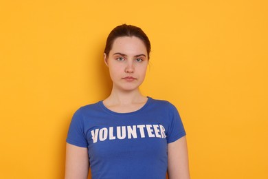 Photo of Portrait of woman in t-shirt with word Volunteer on orange background