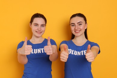 Photo of Volunteers showing thumbs up on orange background