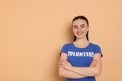 Photo of Portrait of smiling volunteer with crossed arms on beige background. Space for text