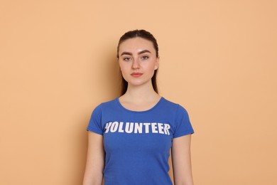 Photo of Portrait of woman in t-shirt with word Volunteer on beige background