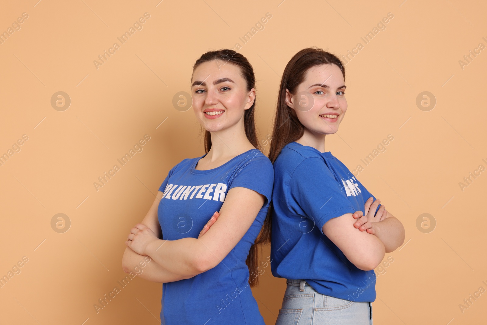 Photo of Portrait of smiling volunteers with crossed arms on beige background