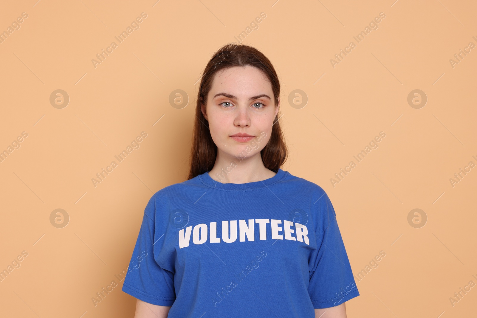 Photo of Portrait of woman in t-shirt with word Volunteer on beige background