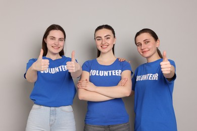 Photo of Team of volunteers showing thumbs up on grey background