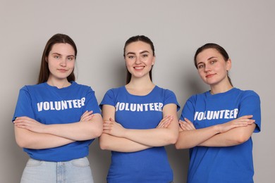 Portrait of volunteers with crossed arms on grey background