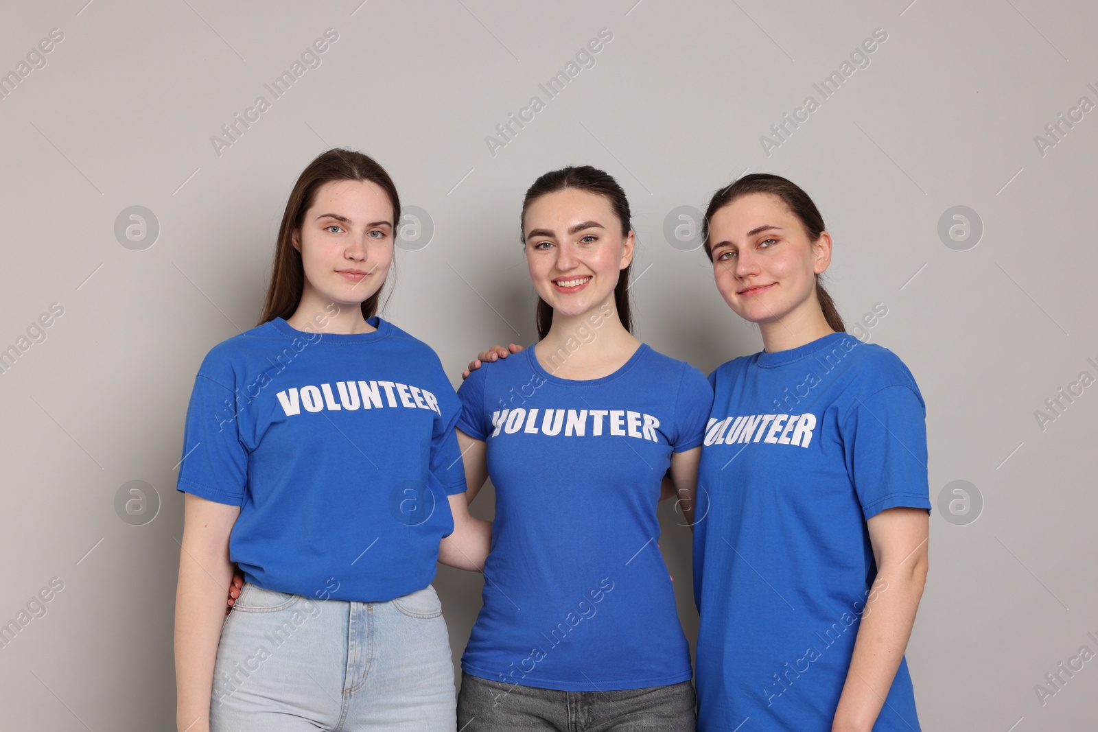 Photo of Portrait of smiling volunteers on grey background