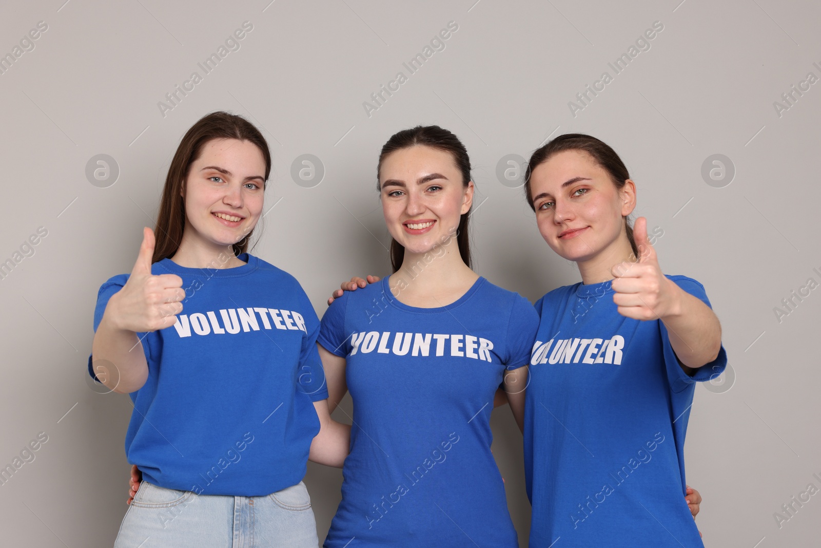 Photo of Team of volunteers showing thumbs up on grey background