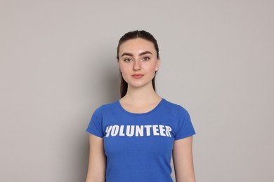 Photo of Portrait of woman in t-shirt with word Volunteer on grey background