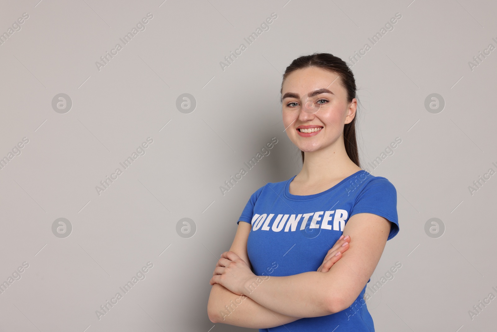 Photo of Portrait of smiling volunteer with crossed arms on grey background. Space for text