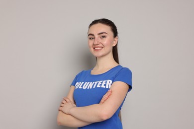 Photo of Portrait of smiling volunteer with crossed arms on grey background