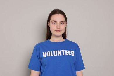 Photo of Portrait of woman in t-shirt with word Volunteer on grey background