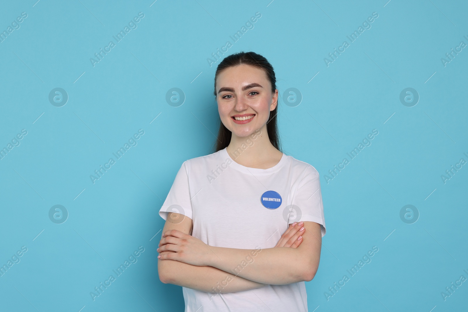 Photo of Portrait of smiling volunteer with crossed arms on light blue background