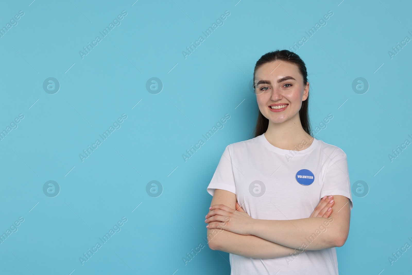 Photo of Portrait of smiling volunteer with crossed arms on light blue background. Space for text