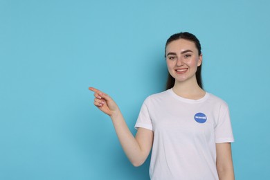 Photo of Portrait of smiling volunteer pointing at something on light blue background. Space for text