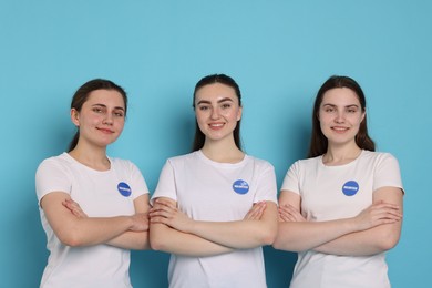 Photo of Team of smiling volunteers with crossed arms on light blue background