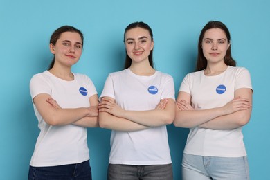 Photo of Team of smiling volunteers with crossed arms on light blue background