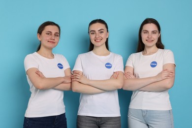 Photo of Team of smiling volunteers with crossed arms on light blue background