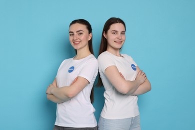 Photo of Smiling volunteers with crossed arms on light blue background