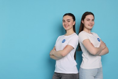 Smiling volunteers with crossed arms on light blue background. Space for text