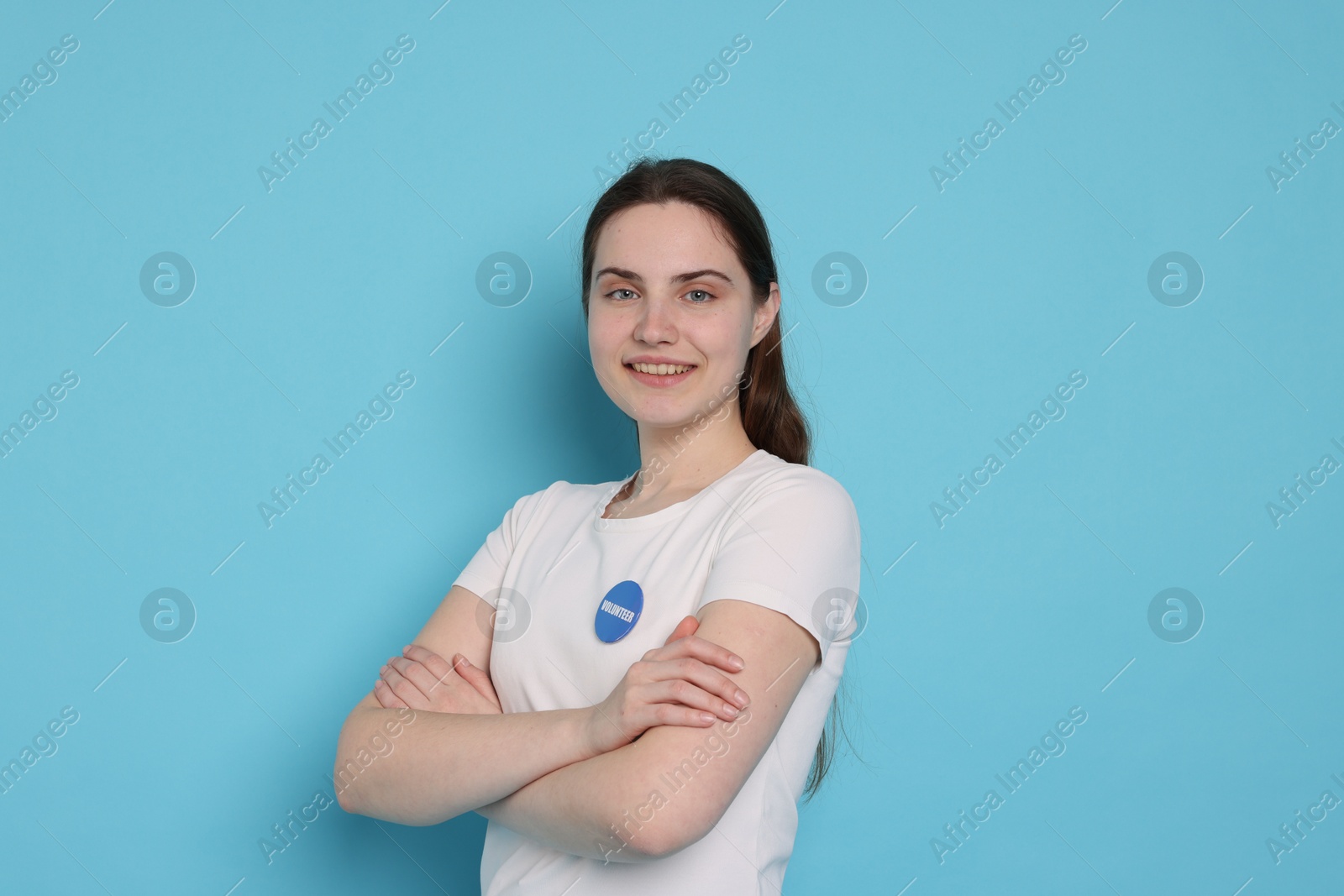 Photo of Portrait of smiling volunteer with crossed arms on light blue background