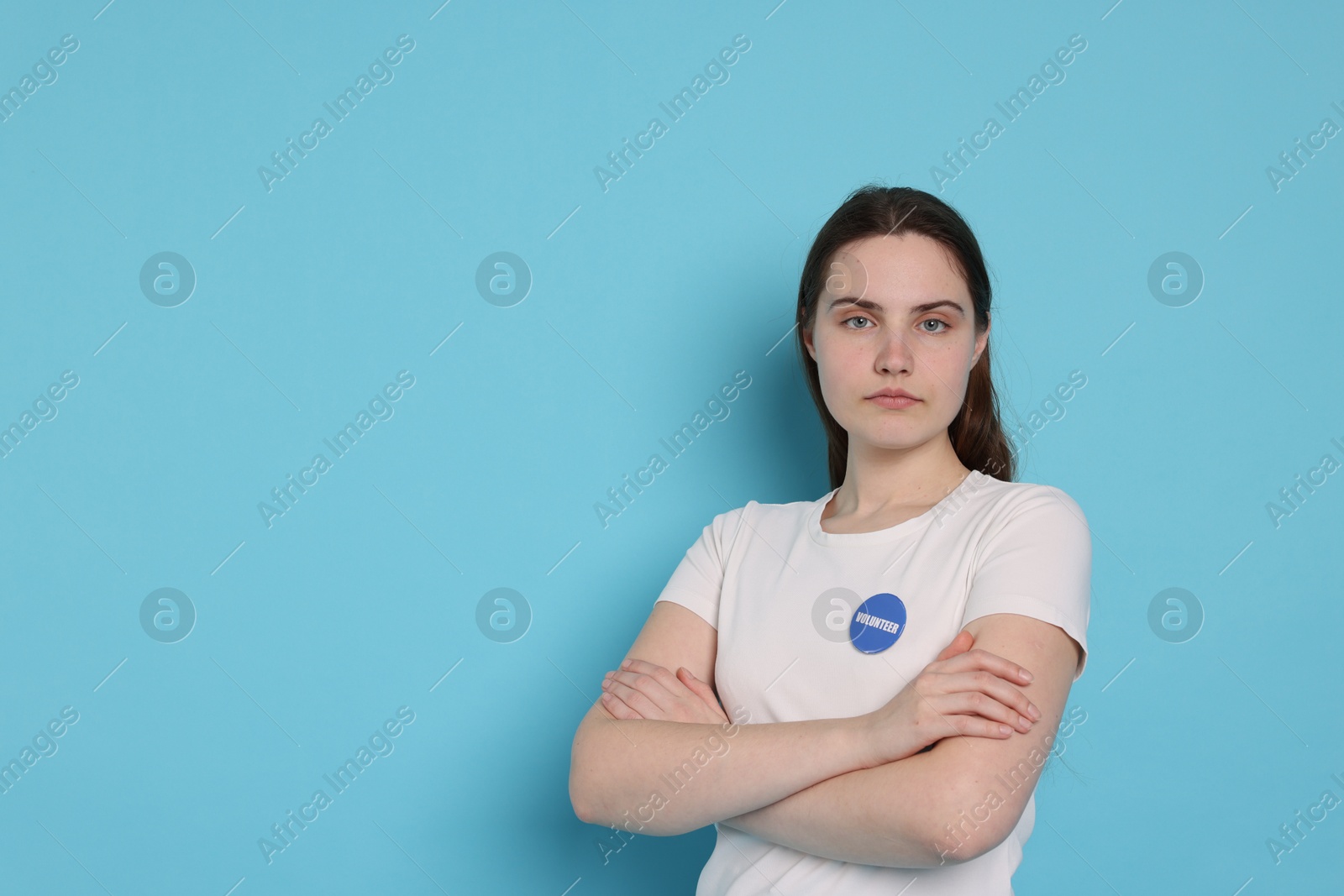 Photo of Portrait of volunteer with crossed arms on light blue background. Space for text