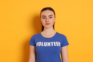 Photo of Portrait of woman in t-shirt with word Volunteer on orange background