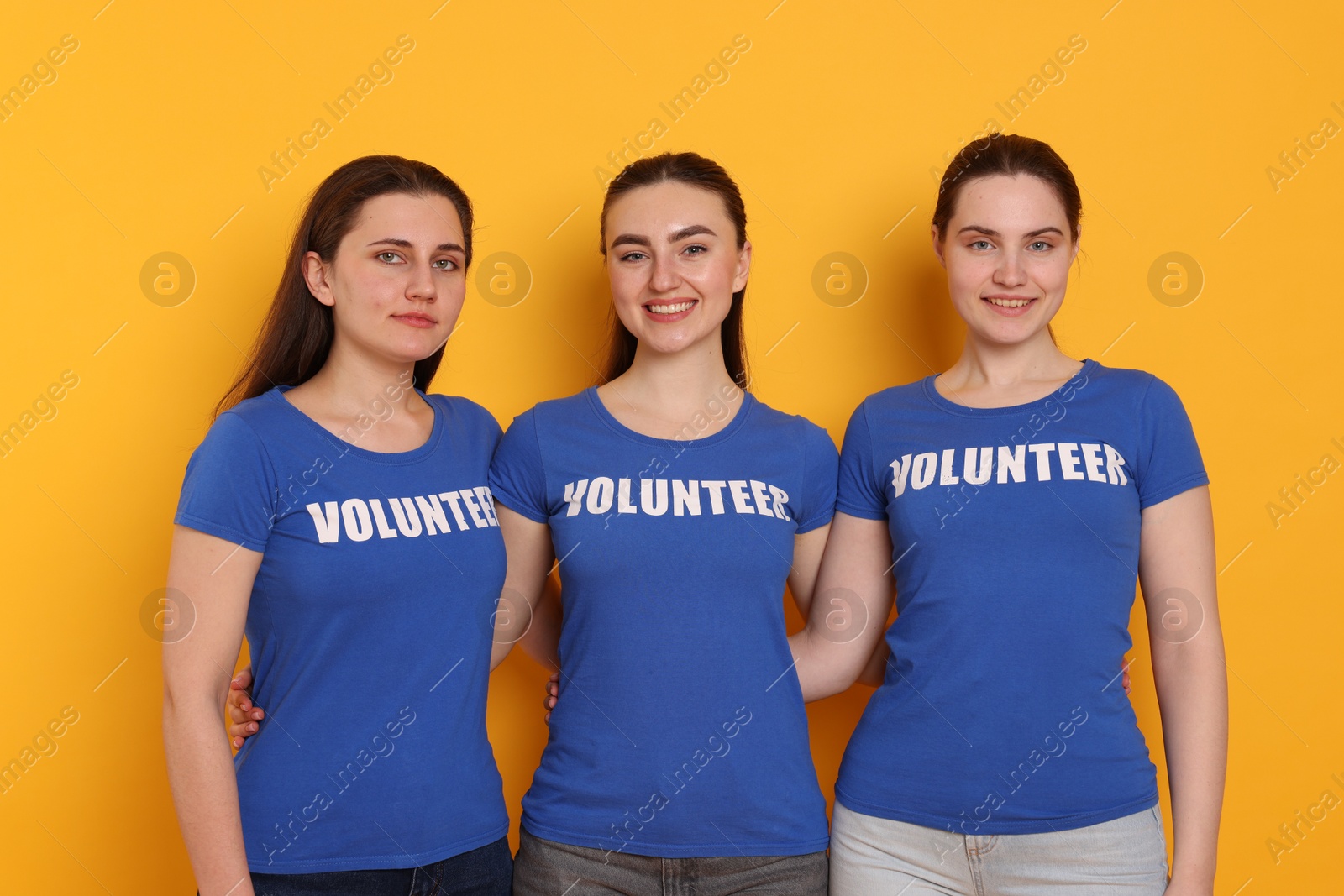 Photo of Team of smiling volunteers on orange background