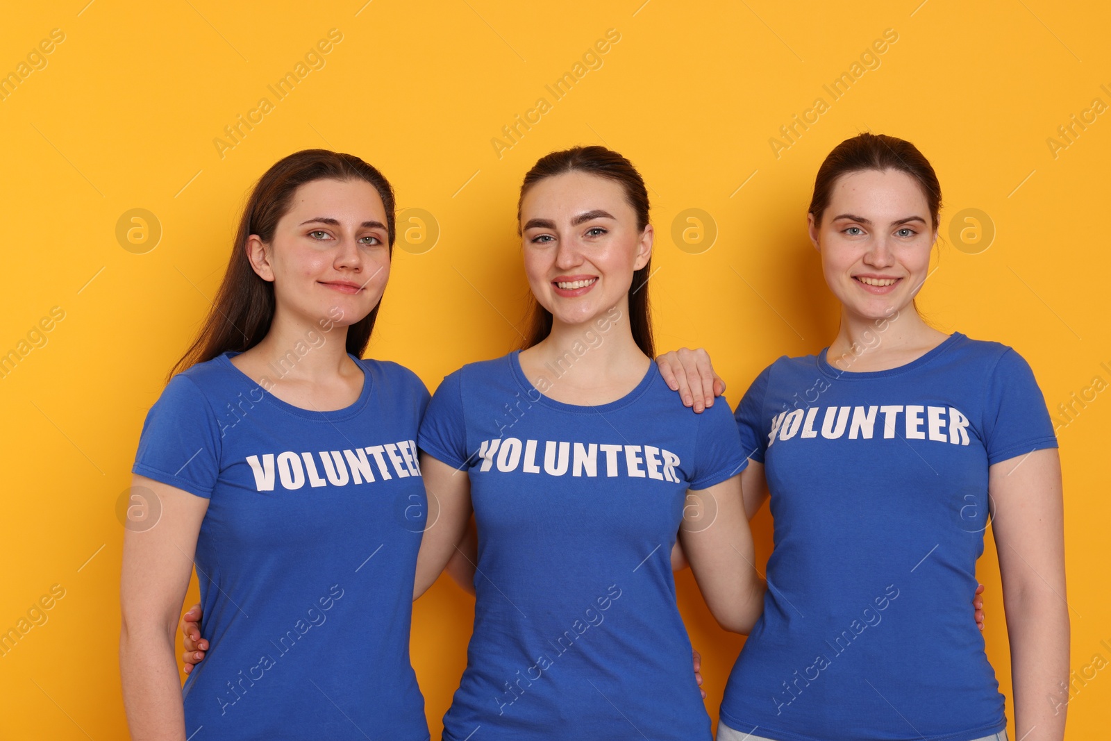 Photo of Team of smiling volunteers on orange background