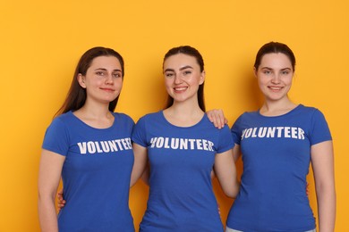 Photo of Team of smiling volunteers on orange background