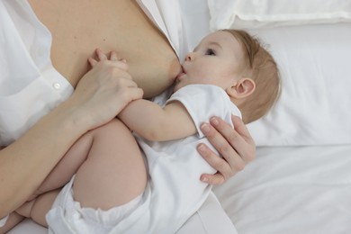 Photo of Mother breastfeeding her little baby on bed at home, closeup