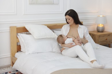 Photo of Mother breastfeeding her little baby on bed at home