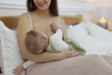 Photo of Mother breastfeeding her little baby on bed at home, closeup